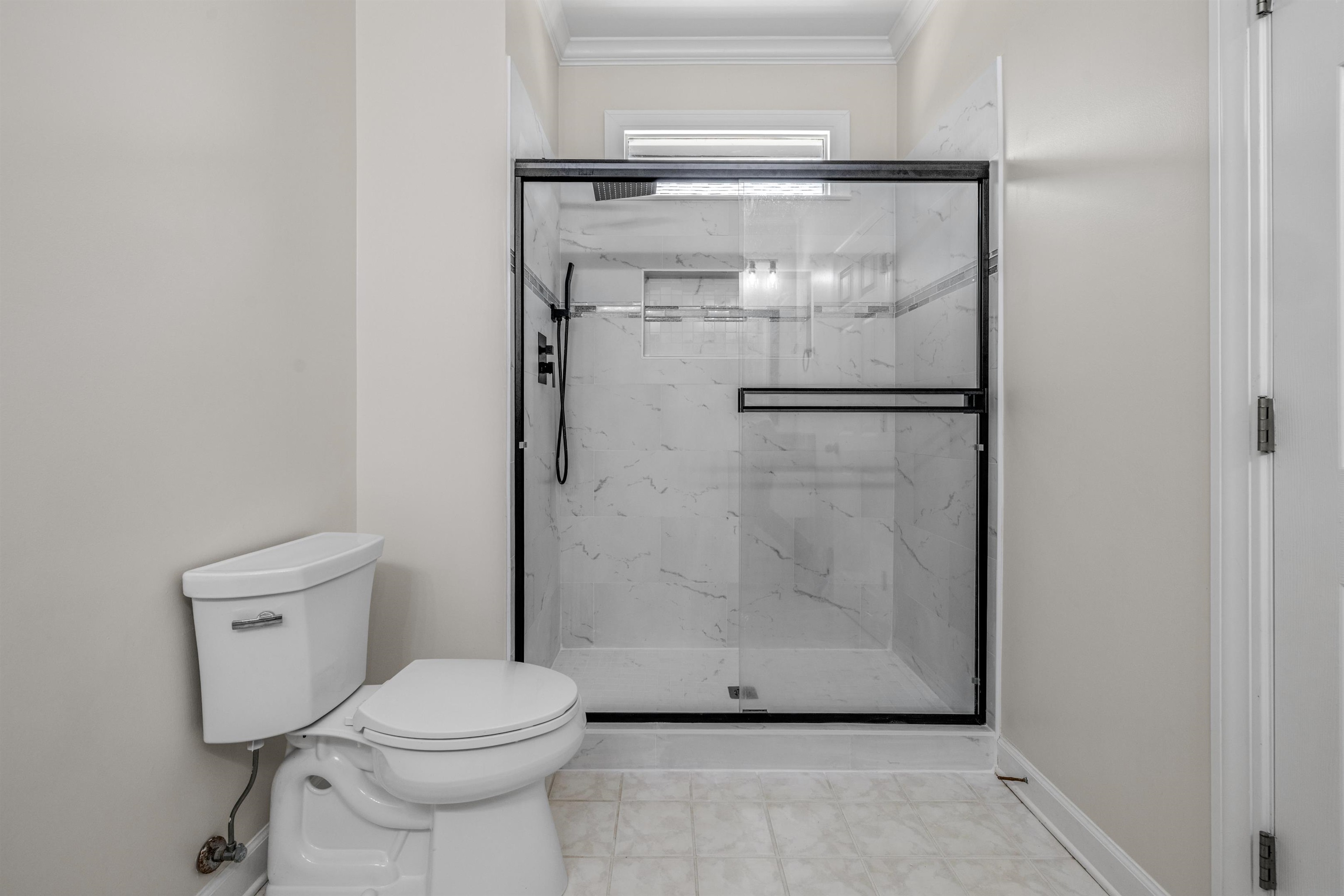 921 Harbor View Drive Memphis, TN 38103 - Photo 27 of 33 Contemporary bathroom featuring a spacious shower with black-framed glass enclosure, white marble-look tile surround, and matte black fixtures
