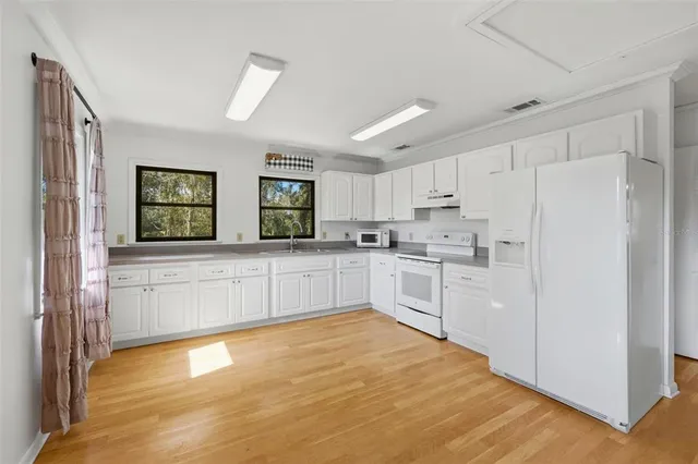 a kitchen with stainless steel appliances a refrigerator sink and white cabinets