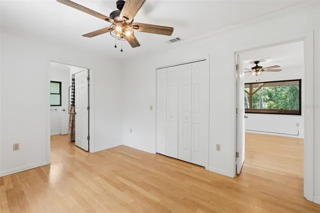 a view of an empty room with window a ceiling fan and wooden floor