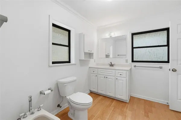 a bathroom with a toilet a sink a mirror and a window