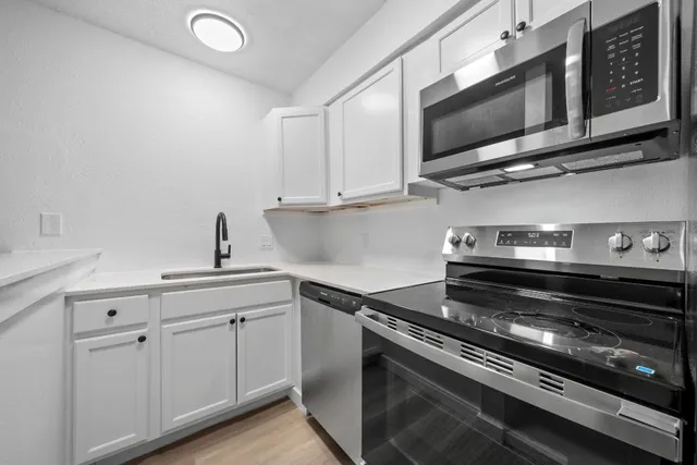 a kitchen with stainless steel appliances a stove a microwave and sink