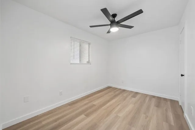 an empty room with a window and a fan