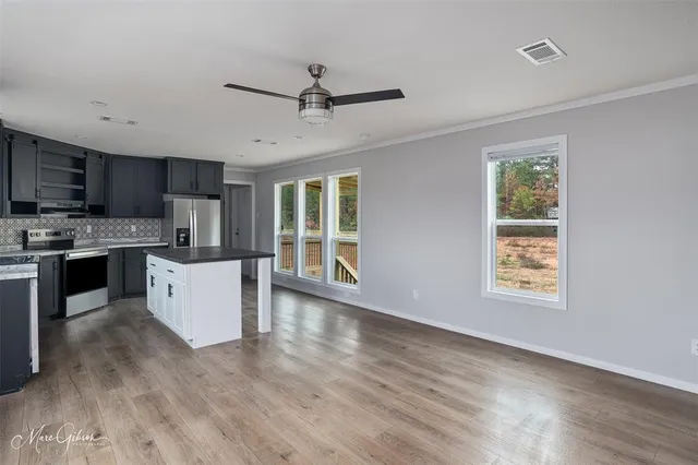 a large kitchen with stainless steel appliances granite countertop a stove a sink dishwasher a microwave oven with cabinets and wooden floor