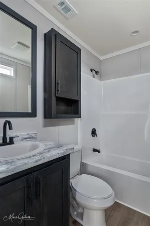 a bathroom with a granite countertop toilet sink and mirror