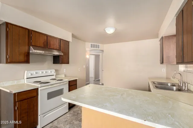 a kitchen with stainless steel appliances a sink a stove a refrigerator cabinets and a counter top space