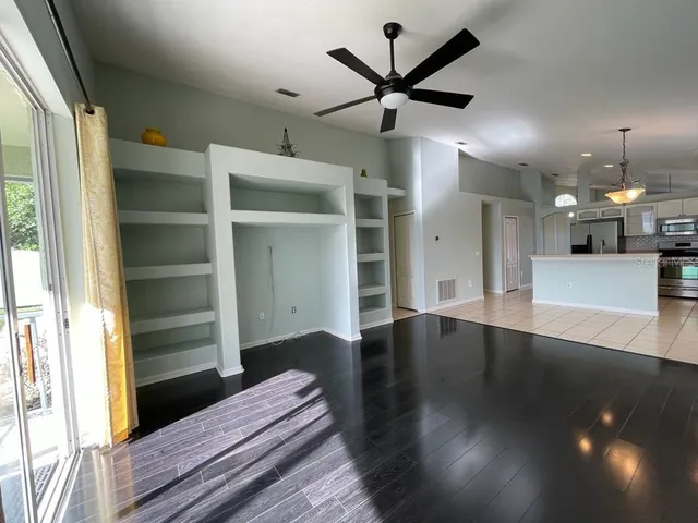 a view of a hallway with wooden floor and a ceiling fan