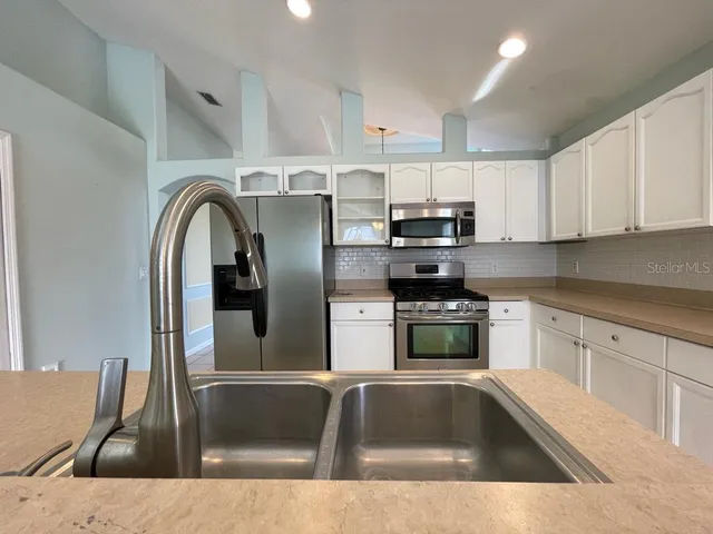 a kitchen with stainless steel appliances granite countertop a sink a stove and cabinets