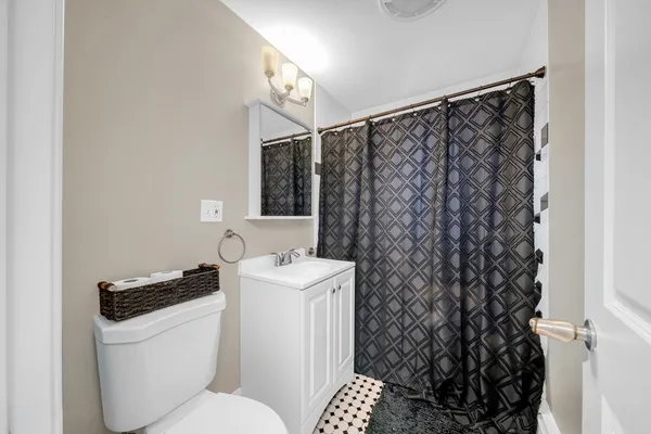 a bathroom with a toilet a sink and a shower curtain