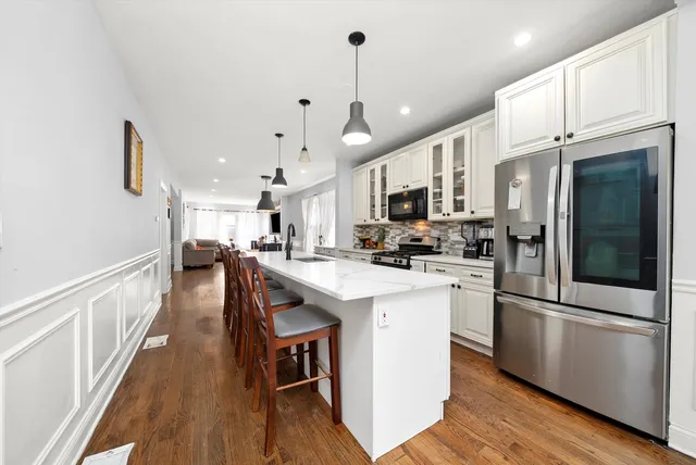 a kitchen with stainless steel appliances granite countertop a sink a stove and a wooden floors