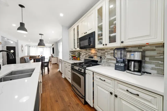 a kitchen with stainless steel appliances granite countertop a sink a stove top oven a counter space and cabinets