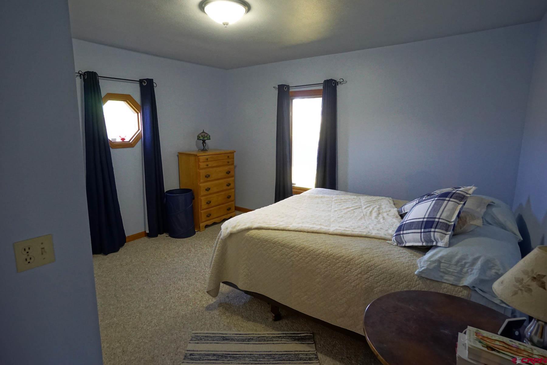 6733 2050th Road Delta, CO 81416 - Photo 11 of 32 a bedroom with a bed and a mirror on dresser