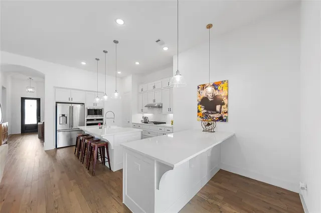 a large white kitchen with a large island oven a sink stainless steel appliances and cabinets