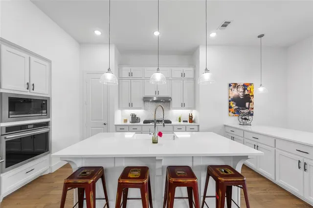 a kitchen with a refrigerator a sink and wooden floor