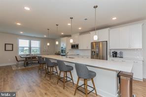 44782 Tiverton Square Ashburn, VA 20147 - Photo 4 of 26 a kitchen with stainless steel appliances kitchen island granite countertop a stove a sink a refrigerator and white cabinets with wooden floor