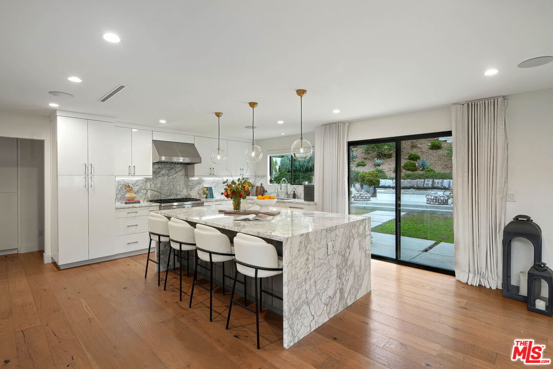 3056 Arrowhead Drive Los Angeles, CA 90068 - Photo 10 of 35 a kitchen with stainless steel appliances granite countertop a stove a refrigerator a sink a dining table and chairs with wooden floor