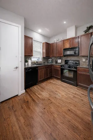 a kitchen with stainless steel appliances granite countertop a stove top oven a sink dishwasher a refrigerator and a refrigerator with wooden floor