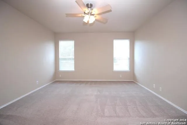 an empty room with windows and ceiling fan
