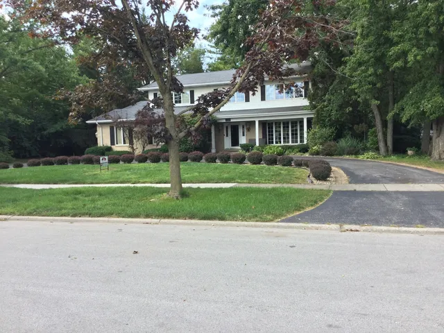 a front view of a house with a garden and trees