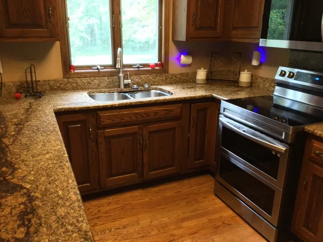 a kitchen with stainless steel appliances granite countertop a stove a sink and a microwave