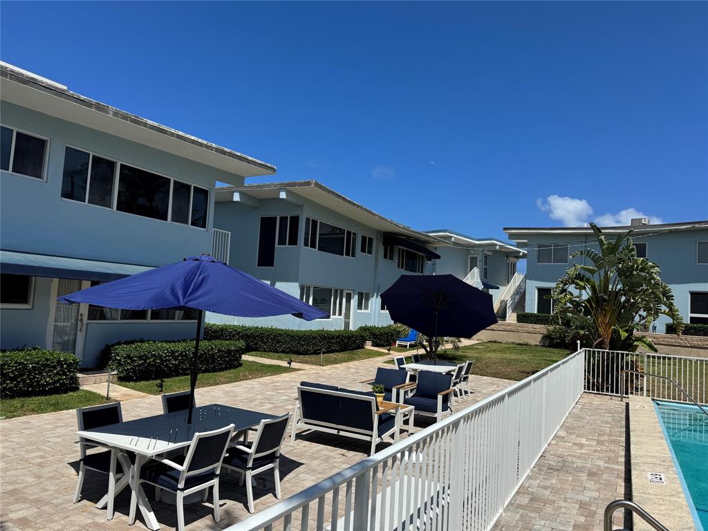 5700 Old Ocean Boulevard, Unit X Ocean Ridge, FL 33435 - Photo 34 of 49 a view of a patio with table and chairs under an umbrella with a fire pit