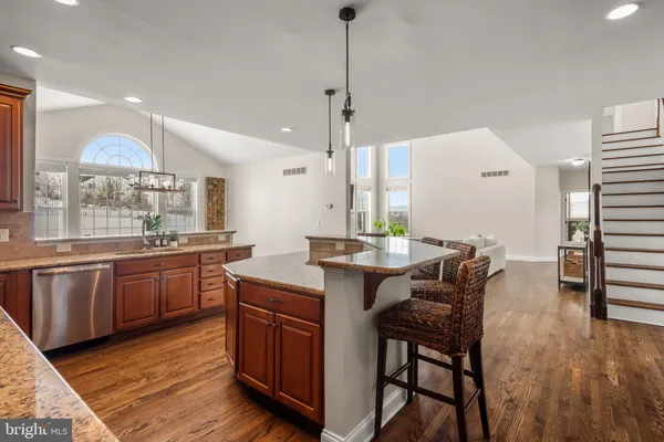 a kitchen with granite countertop a table chairs stove a sink and dishwasher