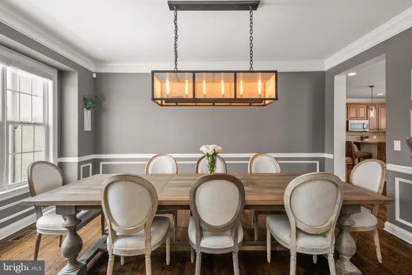 a dining room with chandelier fan and wooden floor