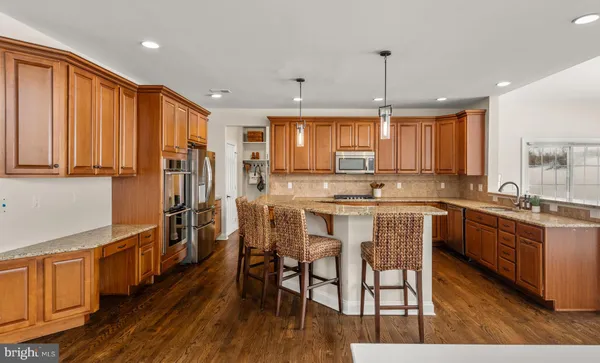 a kitchen with stainless steel appliances granite countertop a stove a sink dishwasher a dining table and chairs with wooden floor