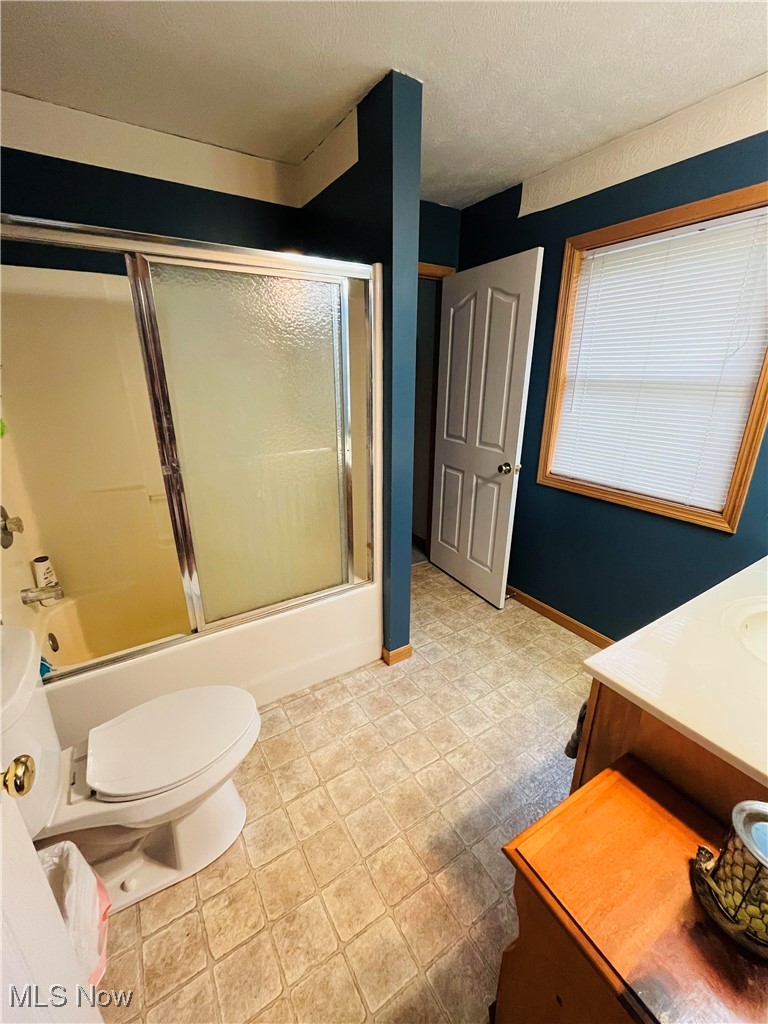 2687 Griggs Road Jefferson, OH 44047 - Photo 20 of 41 Full bathroom featuring shower / bath combination with glass door, vanity, toilet, and a textured ceiling