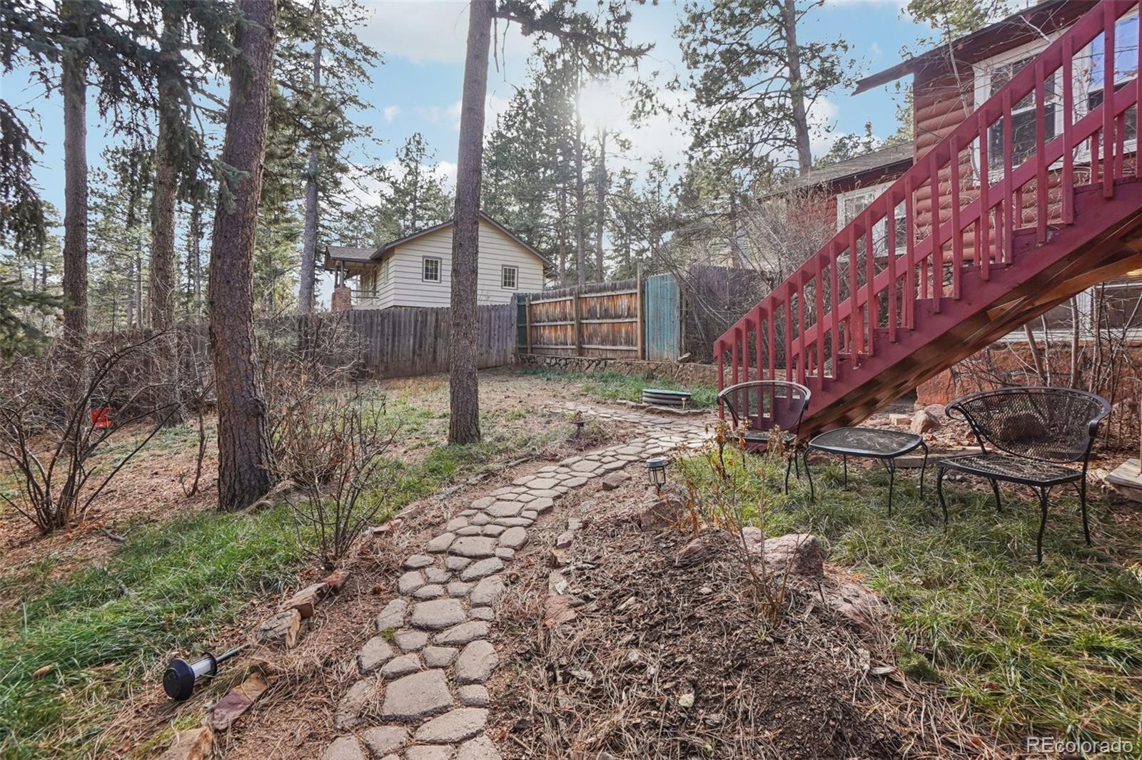 9025 Picabo Road Cascade, CO 80809 - Photo 40 of 44 a backyard of a house with large trees and wooden fence
