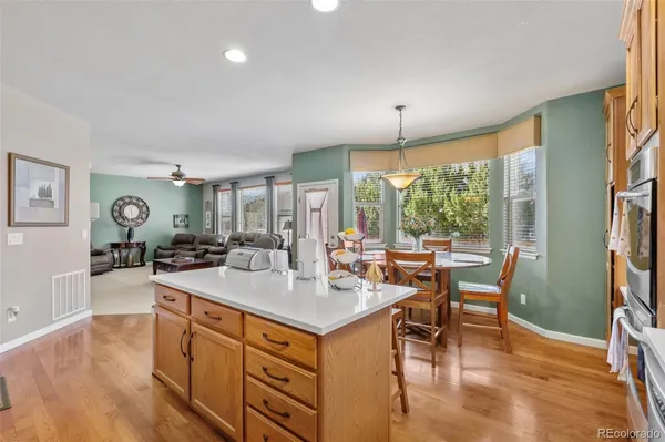 a dining hall with stainless steel appliances granite countertop a stove and a wooden floors