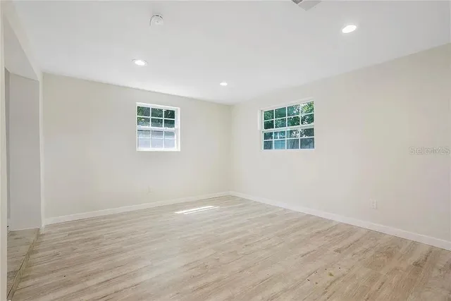 an empty room with wooden floor and window