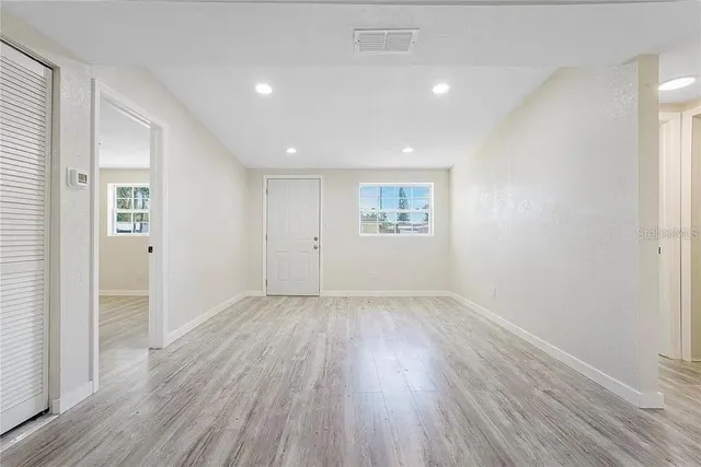 an empty room with wooden floor and windows