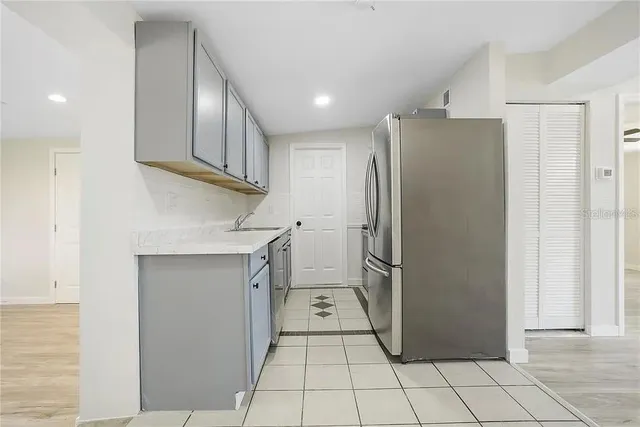 a view of a refrigerator in kitchen and an empty room