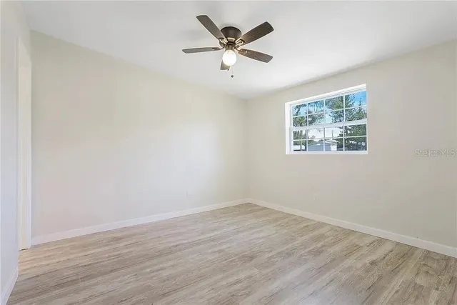 an empty room with wooden floor and ceiling fan