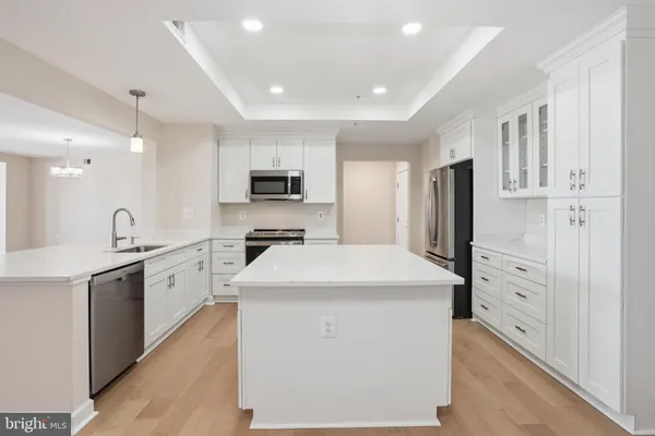 a kitchen that has a lot of white cabinets and stainless steel appliances