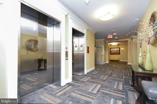 a view of a hallway with wooden floor and a bathroom