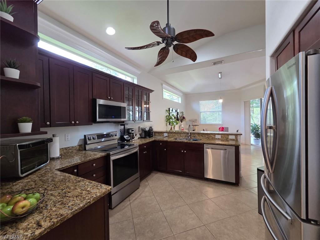 15437 Cortona Way Naples, FL 34120 - Photo 11 of 29 a kitchen with stainless steel appliances granite countertop a stove refrigerator sink and microwave