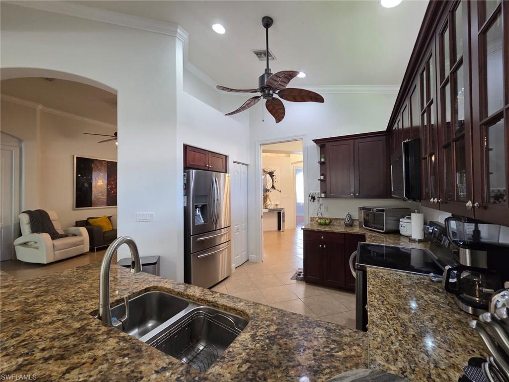 15437 Cortona Way Naples, FL 34120 - Photo 12 of 29 a kitchen with stainless steel appliances granite countertop a sink stove and refrigerator