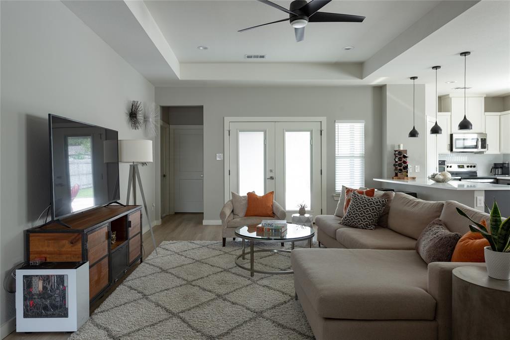 1108 Claude Street Dallas, TX 75203 - Photo 3 of 17 Open-concept living space featuring wood-finish flooring, a tray ceiling with a ceiling fan, and French doors with privacy glass