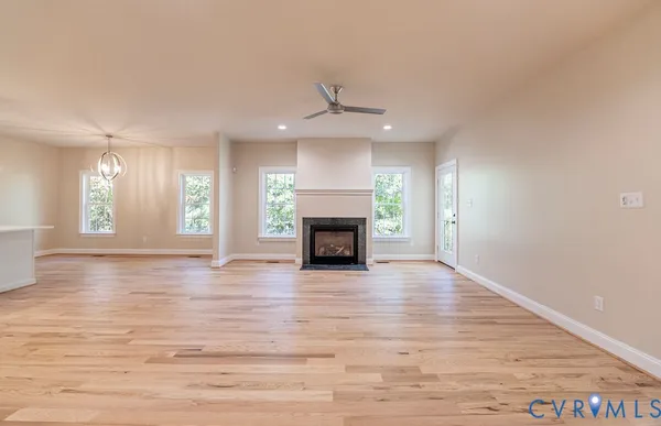 an empty room with wooden floor fireplace and windows