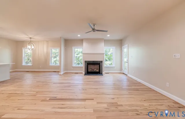 an empty room with wooden floor fireplace and windows