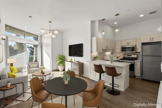 a kitchen with stainless steel appliances kitchen island granite countertop a dining table chairs and a refrigerator