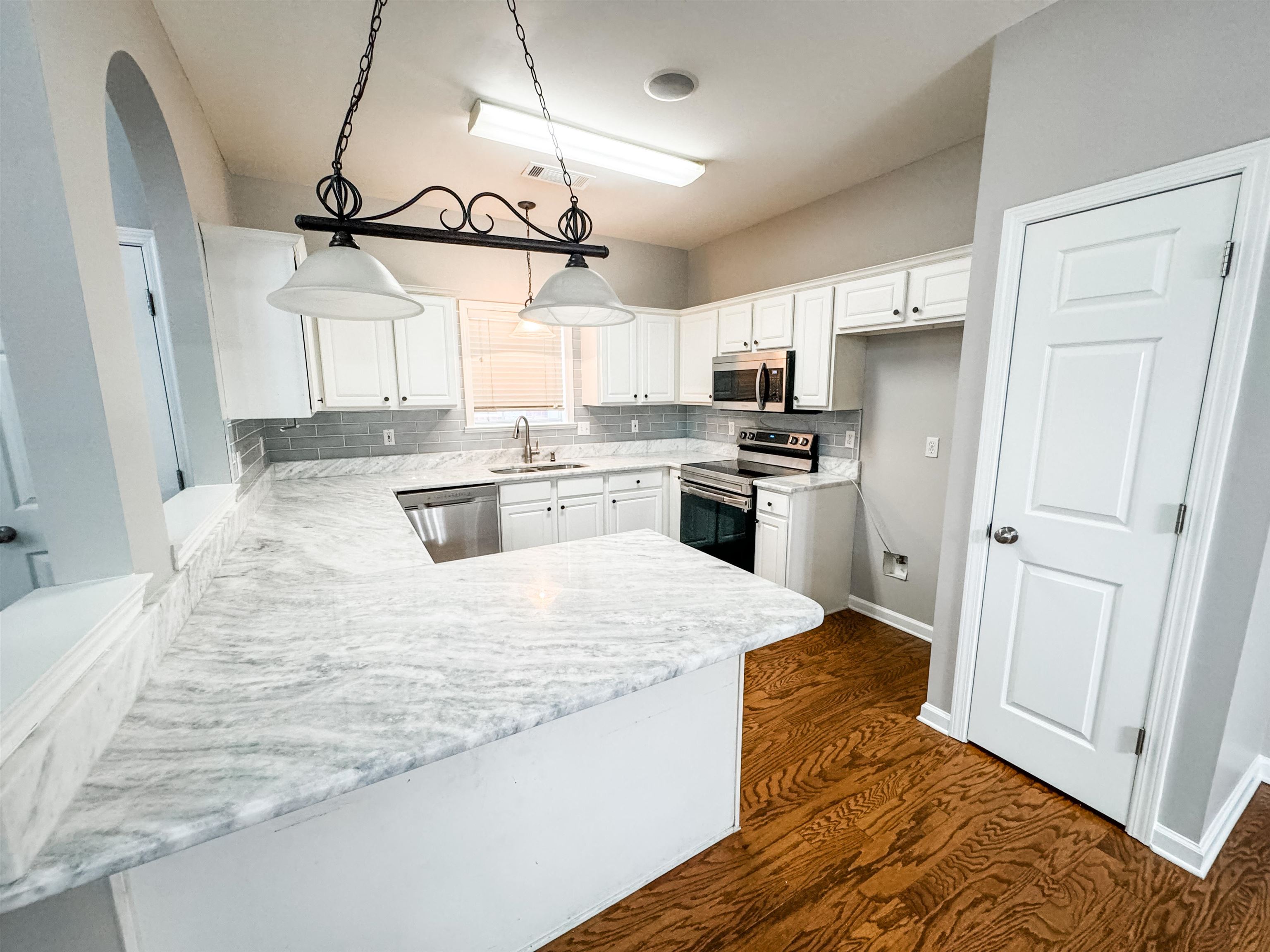4564 Park Ridge Parkway Collierville, TN 38017 - Photo 3 of 12 a large kitchen with stainless steel appliances kitchen island granite countertop a refrigerator a sink dishwasher a stove with white cabinets and wooden floor