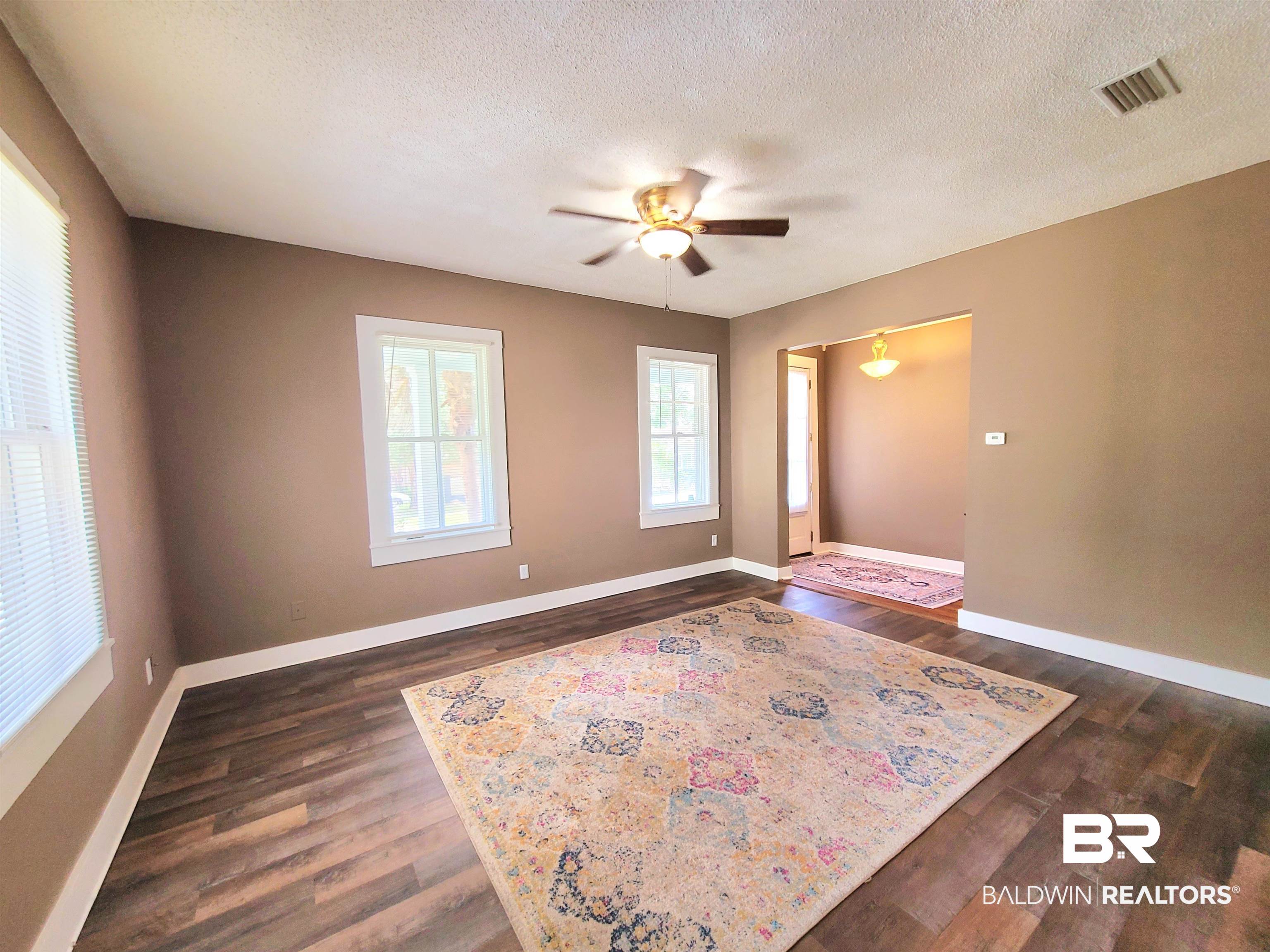 112 Espejo Street Mobile, AL 36604 - Photo 17 of 20 Spare room with a textured ceiling, visible vents, baseboards, dark wood-style flooring, and a ceiling fan