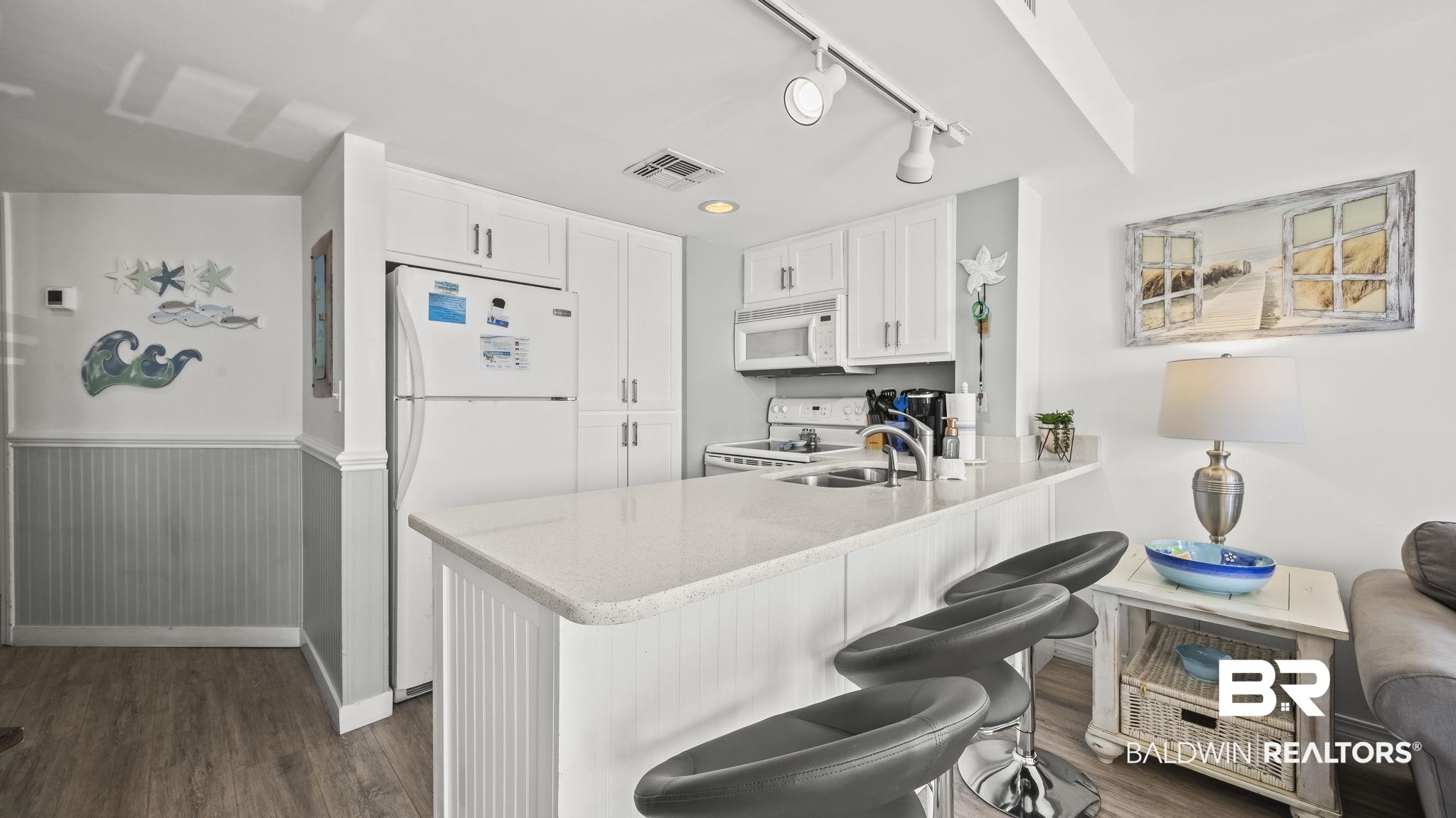 497 Plantation Road, Unit 1247 Gulf Shores, AL 36542 - Photo 6 of 29 Kitchen with white appliances, track lighting, white cabinetry, a kitchen bar, and a peninsula