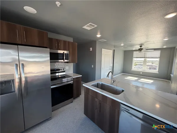 a kitchen with stainless steel appliances granite countertop a sink a stove and a refrigerator