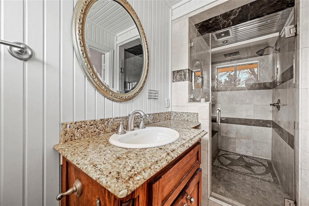 412 West Spinner Road DeSoto, TX 75115 - Photo 8 of 13 Bathroom featuring a granite-topped vanity with a built-in sink, an ornate oval mirror, and a glass-enclosed shower with tiled walls and a mosaic floor