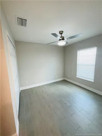 an empty room with chandelier fan and windows