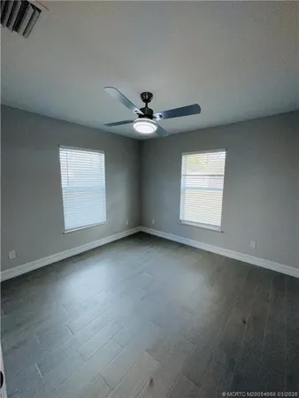 an empty room with windows and ceiling fan