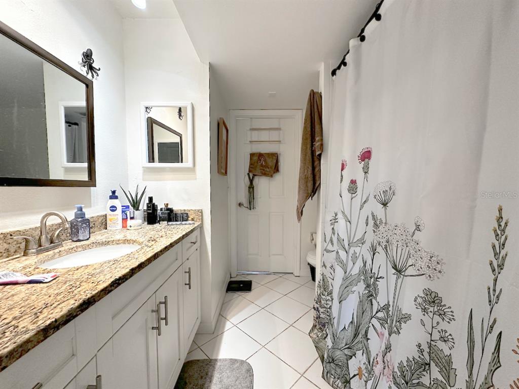 1713 Azalea Court, Unit A Oldsmar, FL 34677 - Photo 27 of 38 a spacious bathroom with a granite countertop shower sink and a mirror